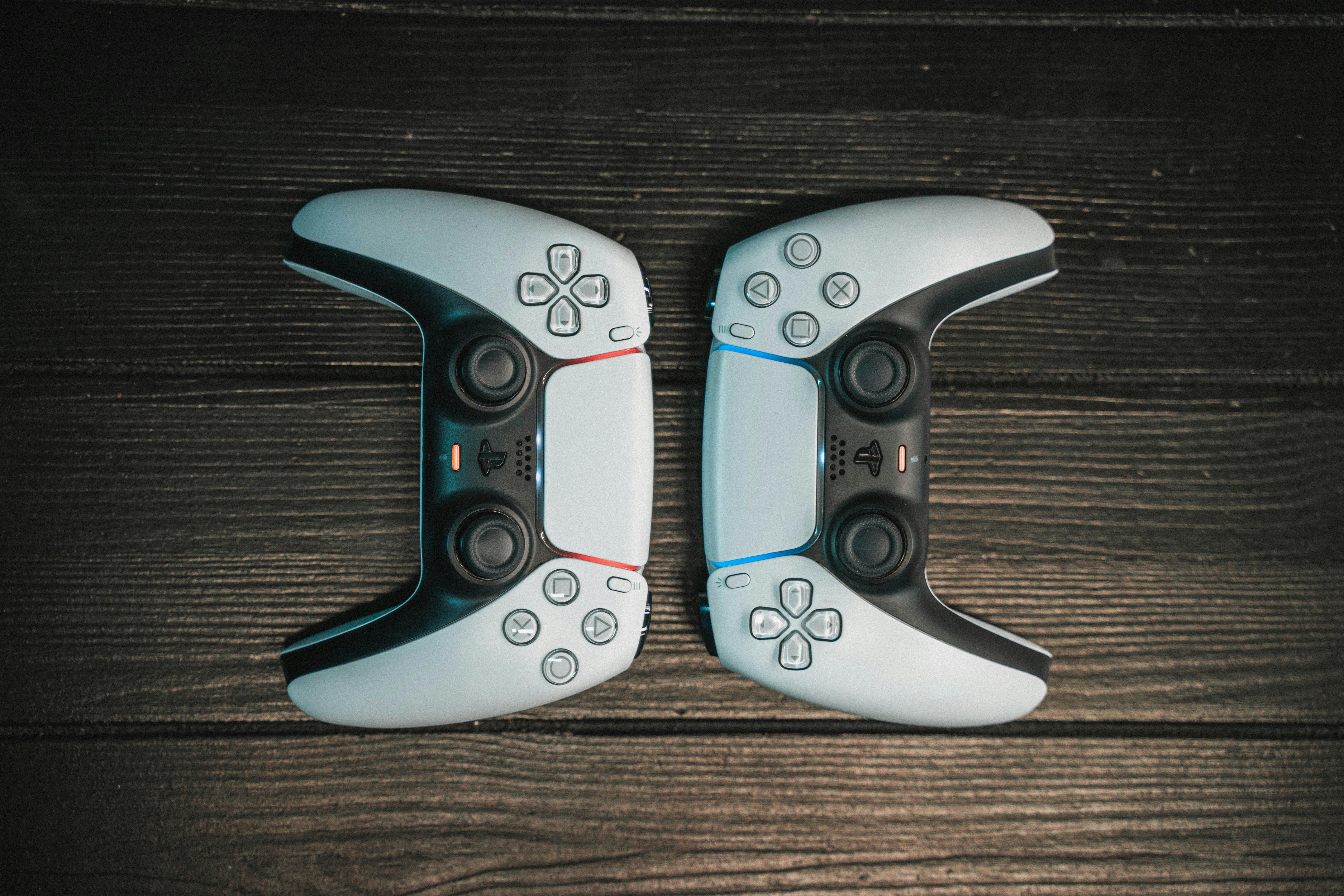 A Pair of Black and White Game Controllers on Wooden Surface