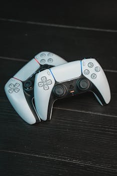 Top view of two white game controllers on a dark wood background, perfect for gaming related concepts.
