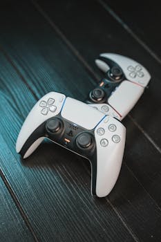 Pair of modern gaming controllers placed stylishly on a dark wooden surface, showcasing technology aesthetics.