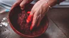 Person Holding Red Round Container