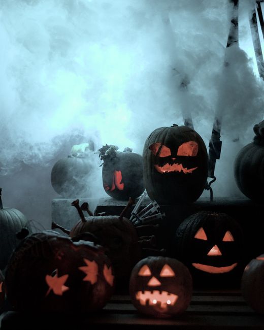 Eerie Halloween scene with glowing jack-o'-lanterns surrounded by smoke and mystery.