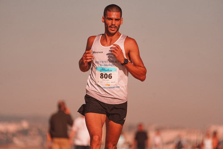 A Man In White Tank Top And Black Shorts Running