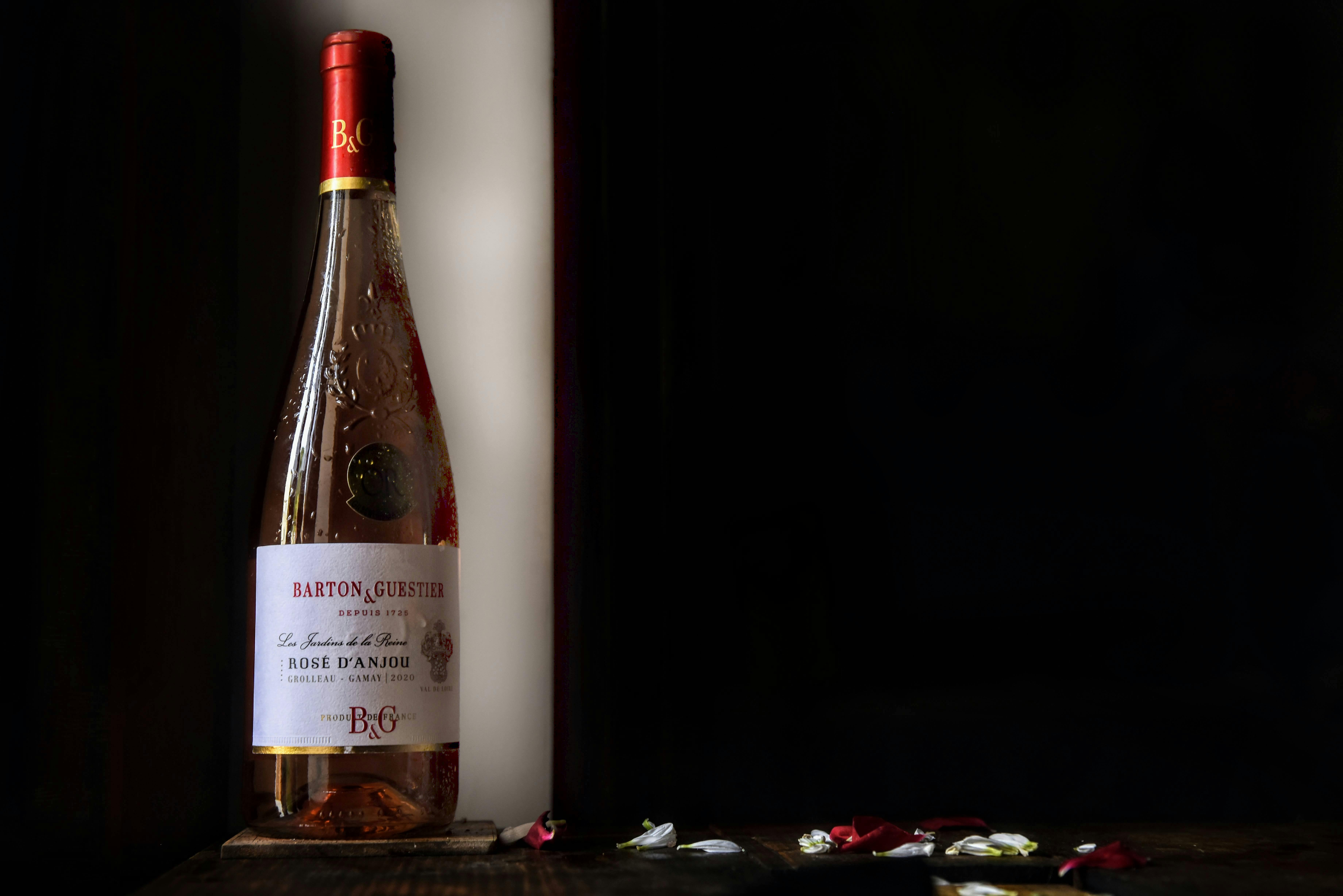 Sophisticated product photo of wine bottle with delicate rose petals on a wooden surface.