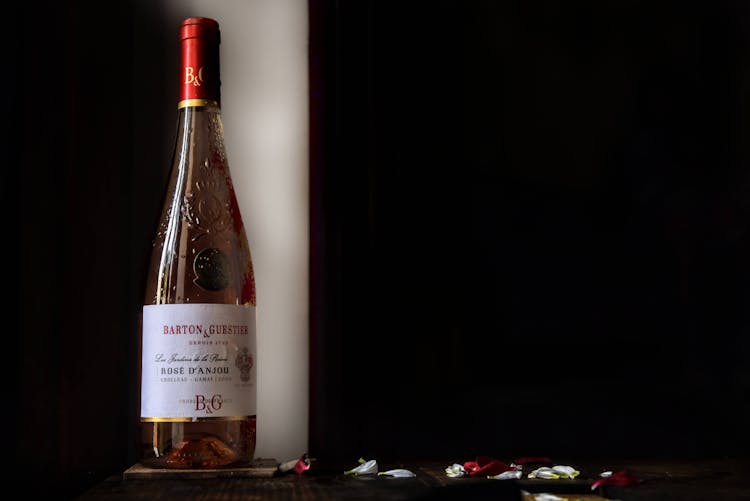 A Bottle Of Barton And Gurstier On Table With Flower Petals