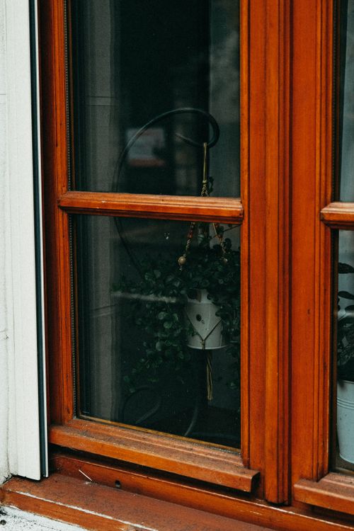 Free A serene view of a wooden window with a hanging plant inside, adding a touch of nature to the space. Stock Photo
