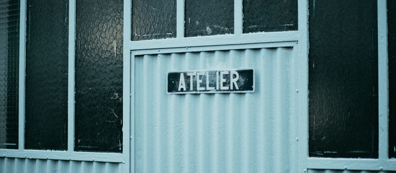 Rustic workshop entrance with 'atelier' sign, showcasing vintage industrial design.