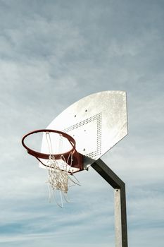 A low angle shot of a basketball hoop with net against a clear blue sky, ideal for sports themes.