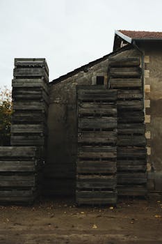 Weathered wooden crates piled high against an old building, evoking a rustic industrial vibe.