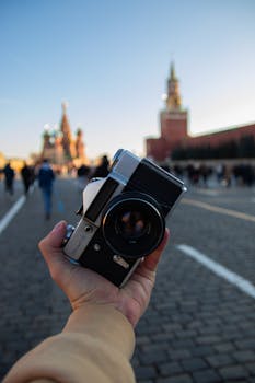 Hand holding a vintage camera with a blurred backdrop of Red Square, Moscow.