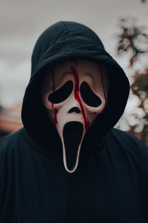 Free Spooky masked individual in a hood with a blood-stained mask, perfect for Halloween themes. Stock Photo