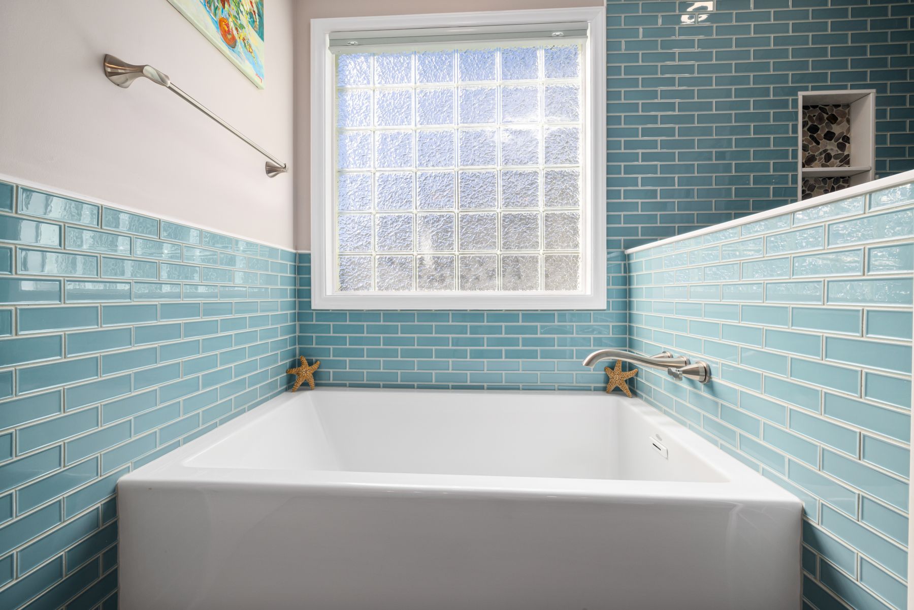 Bright bathroom with turquoise tiled wall and simple white bathtub