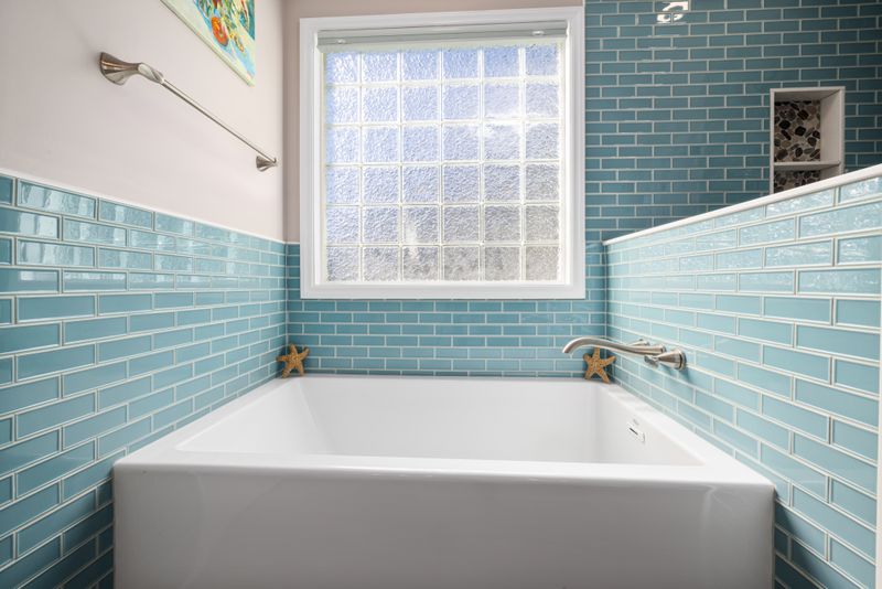 Bright bathroom with turquoise tiled walls and a white bathtub