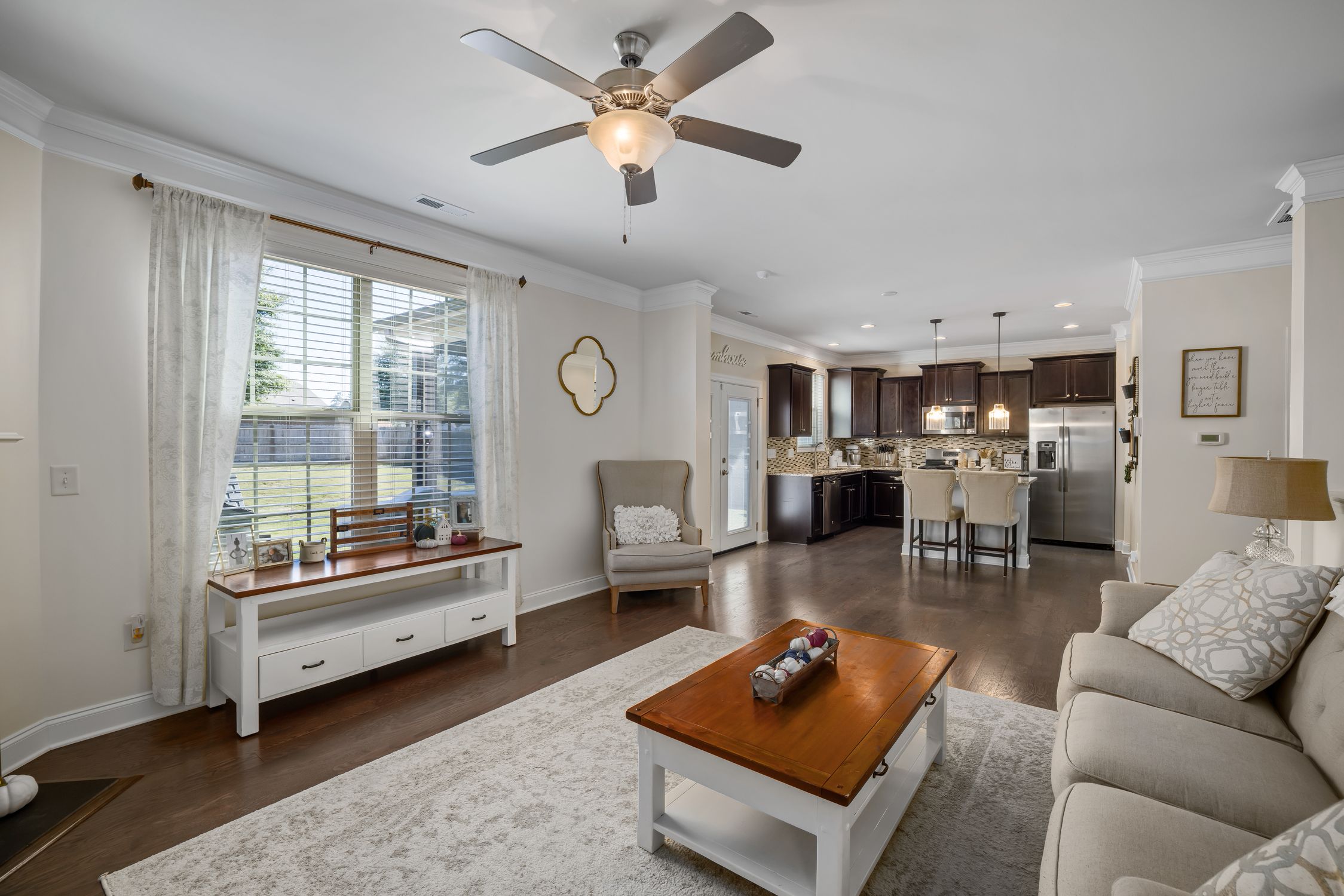 Open-plan living room with wooden flooring and a kitchen in the background