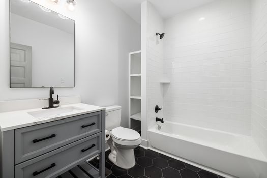 Sleek modern bathroom featuring a white bathtub, sink, toilet, and elegant fixtures.