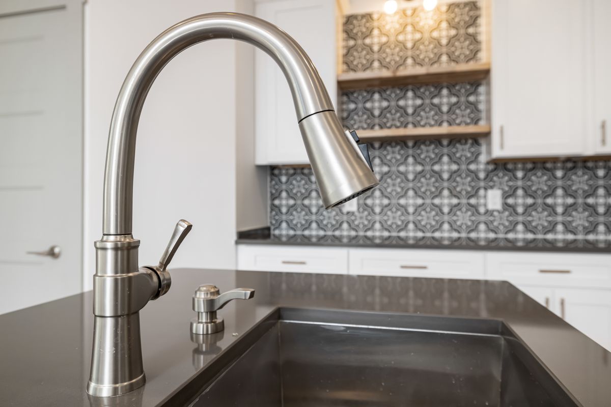 Modern stainless steel kitchen faucet with sleek single-lever handle against a tiled backsplash