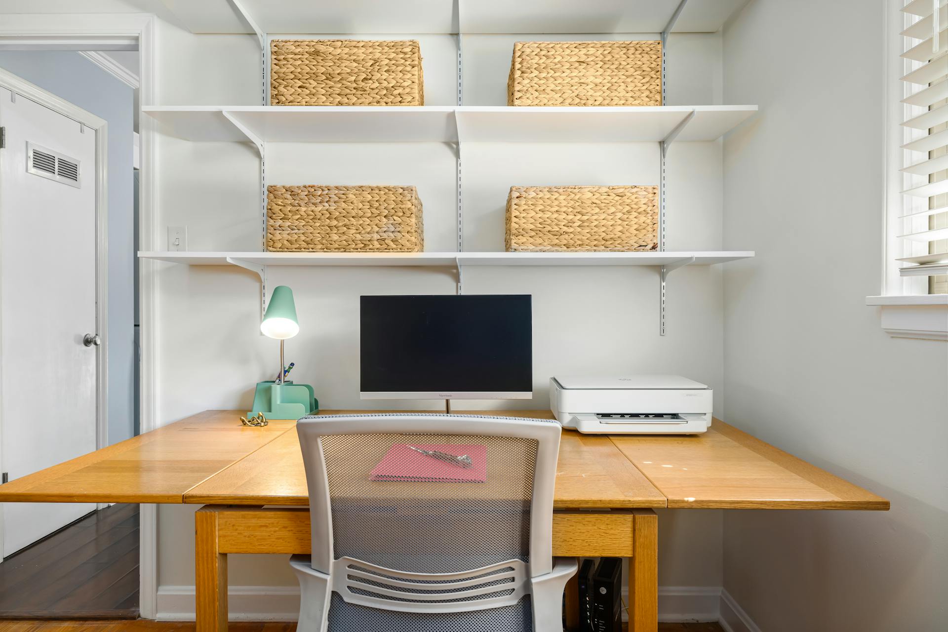 A clean organized home office with desk and shelving