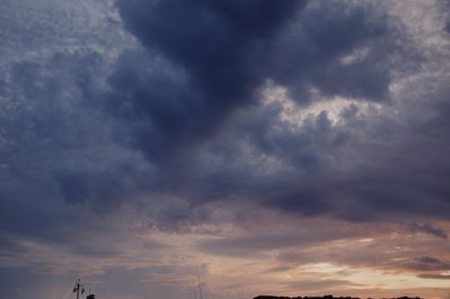 Free A dramatic sky filled with dark clouds at sunset, casting a serene ambiance over the horizon. Stock Photo