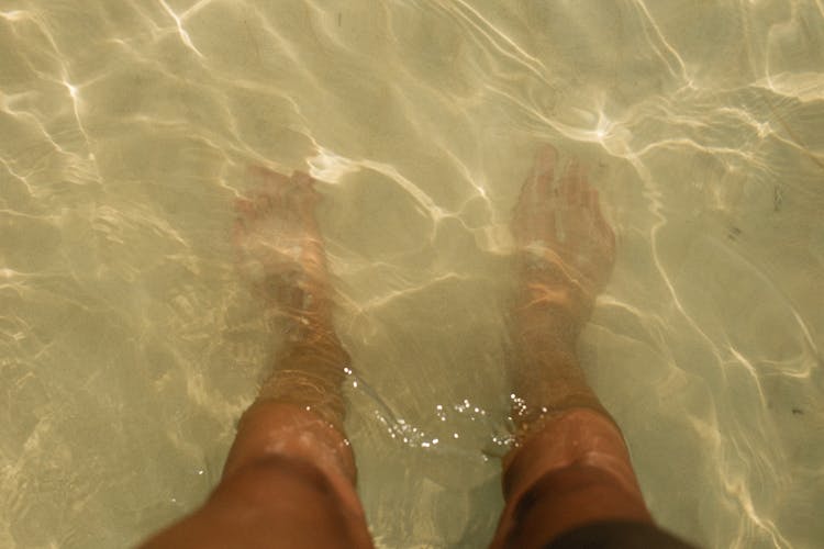 Feet Submerged In Shallow Sea Water