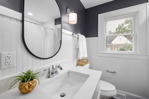 Free Sleek modern bathroom featuring a large mirror, window view, and stylish white interior decor. Stock Photo
