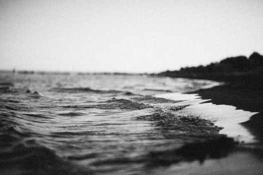 Black and white close-up of gentle waves washing ashore, creating a soothing mood.