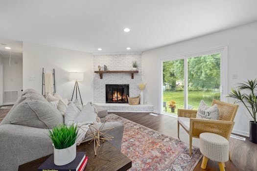 Bright living room featuring a modern fireplace, greenery, and large windows offering a garden view.