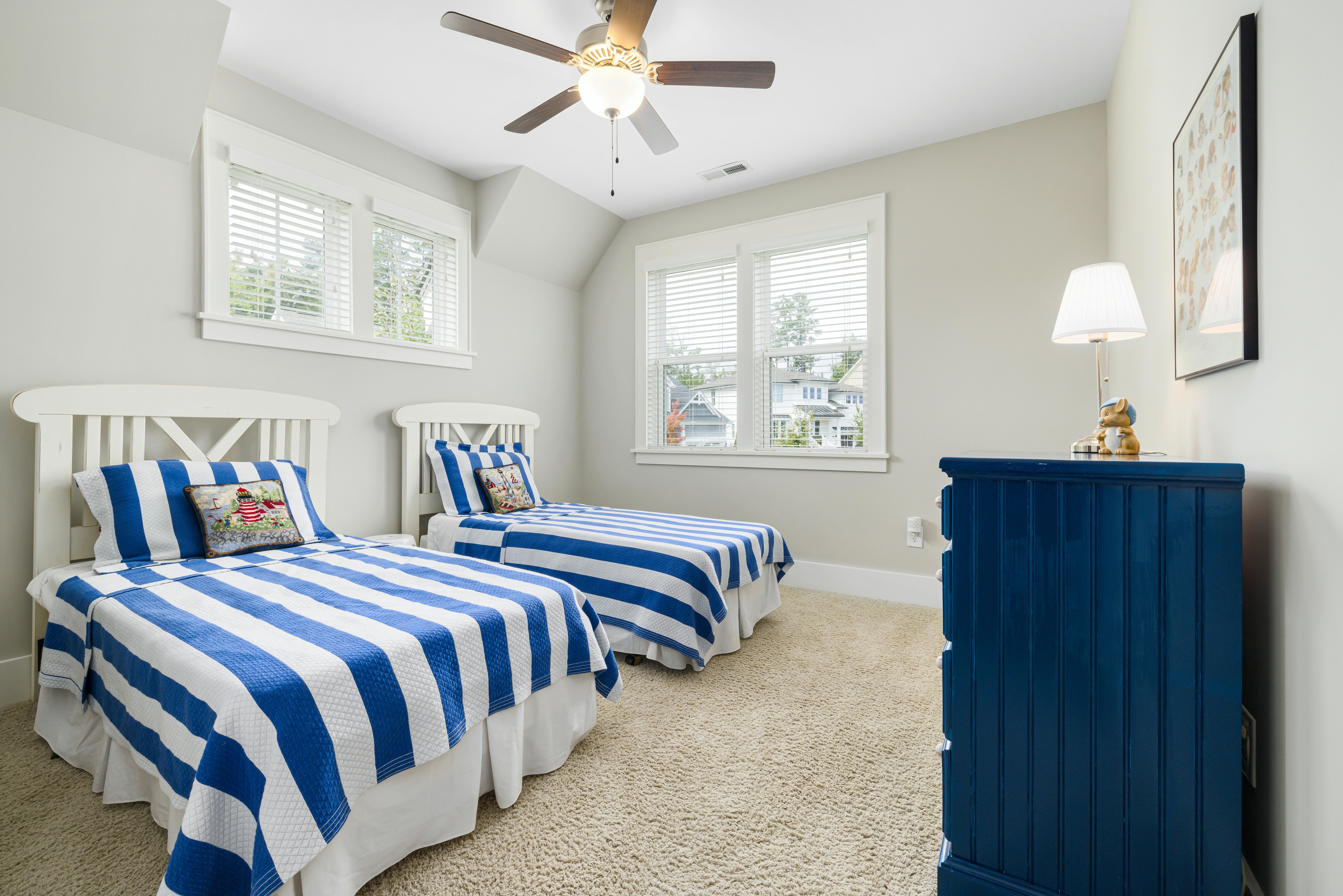 Bright and cozy kids' bedroom featuring twin beds with blue striped bedding and elegant decor.