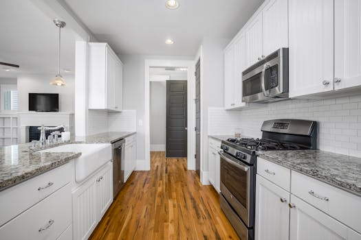 Sleek modern kitchen featuring granite countertops, stainless steel appliances, and wooden flooring.