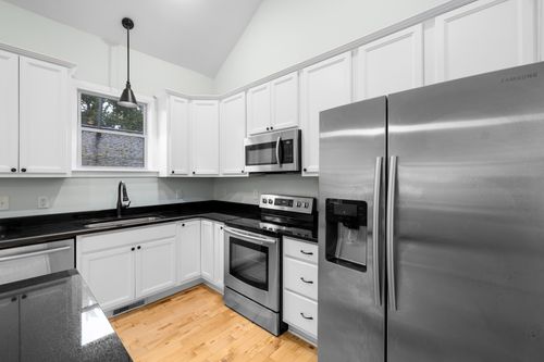 Free A sleek and modern kitchen featuring white cabinets, stainless steel appliances, and black countertops. Stock Photo