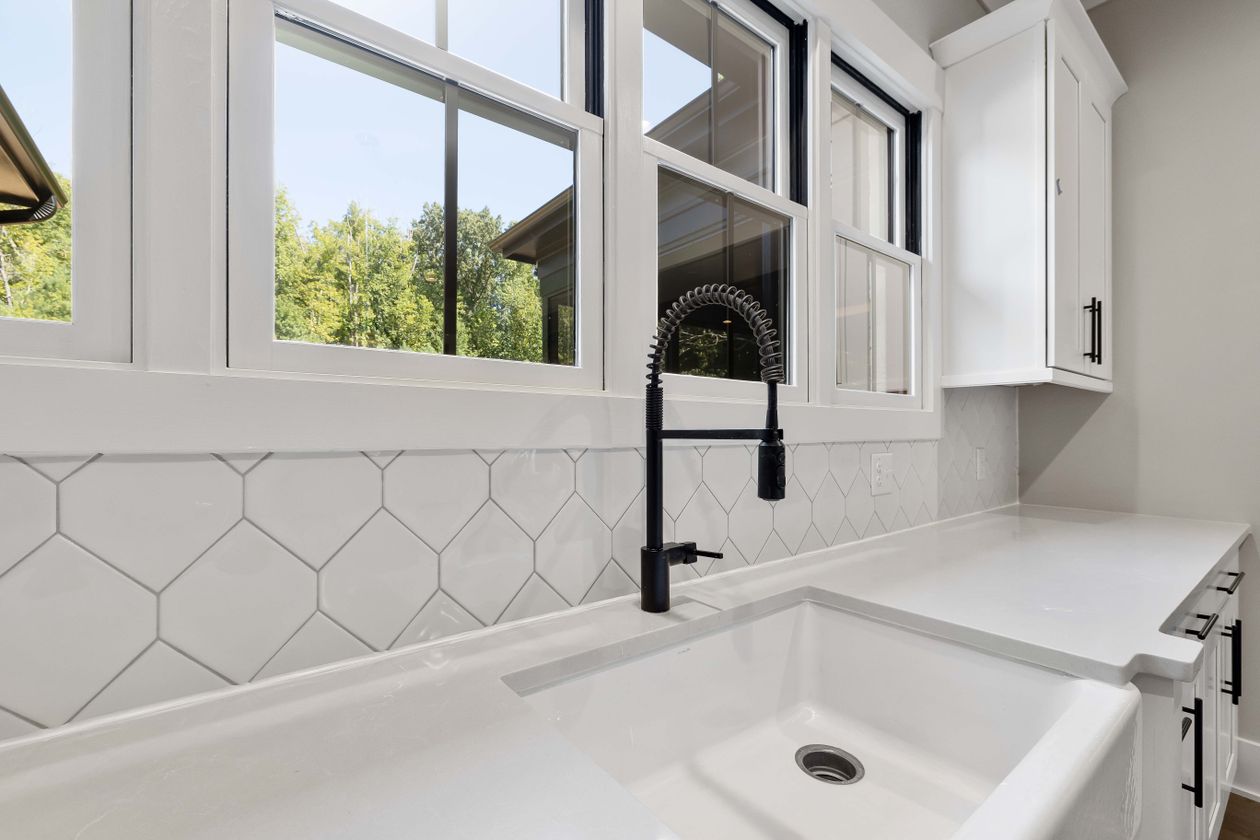White farmhouse sink with black faucet White ceramic farmhouse sink with a matte black faucet in a bright kitchen