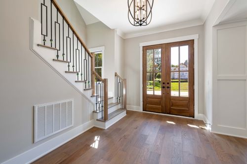 Free Elegant and spacious house entrance featuring wooden doors and staircase. Stock Photo