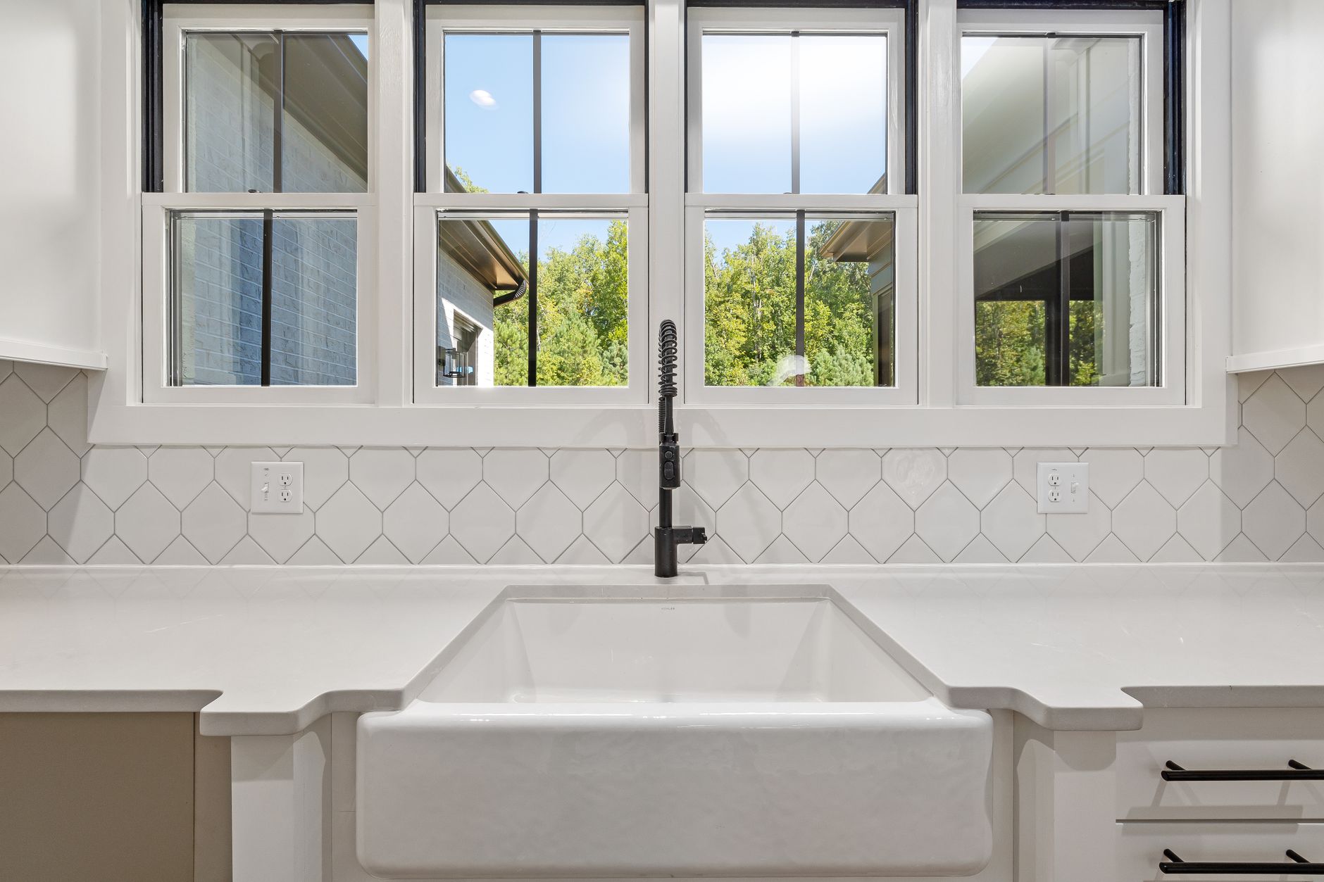Bright kitchen interior featuring modern sink and large window with outdoor view.
