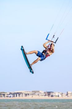 Thrilling kiteboarding scene with a man performing an aerial stunt over the water.