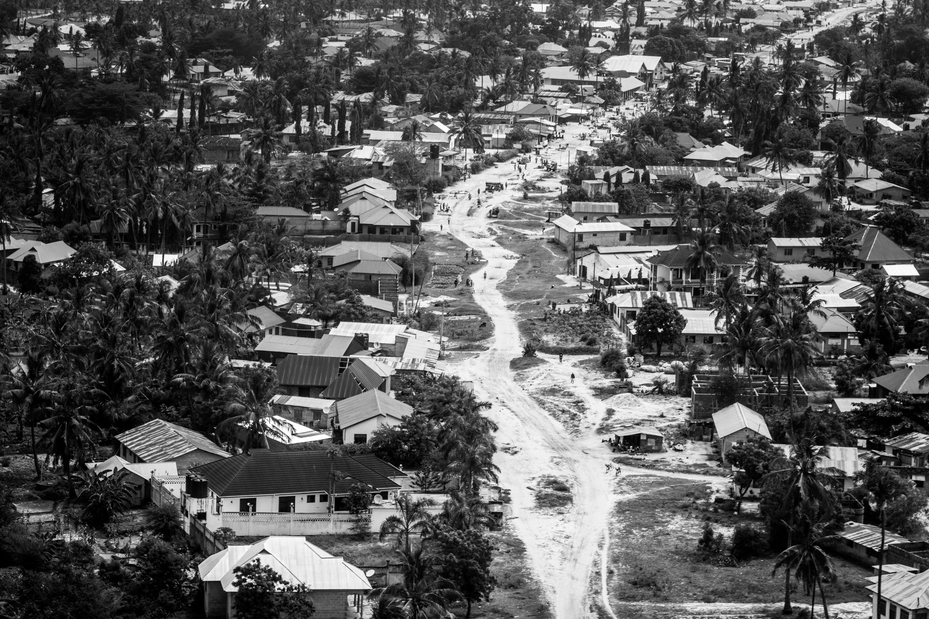 Black and white aerial view of a Tanzanian suburb with houses and unpaved roads.