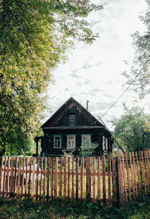 Free A picturesque wooden cabin in rural Bashkortostan, Russia, surrounded by a wooden fence and lush greenery. Stock Photo