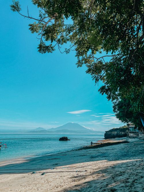Free A serene beach scene in Bali with clear waters and a view of Mount Agung. Stock Photo