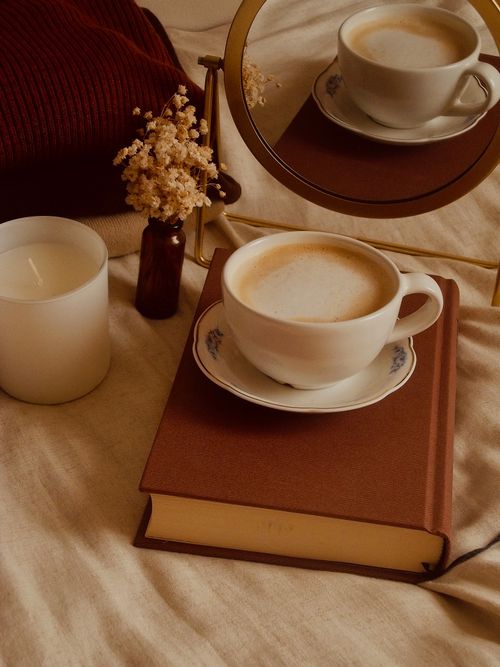Free Warm and cozy scene with coffee, books, and candle in a minimalist style. Stock Photo
