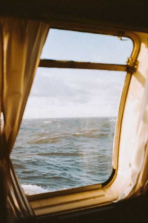 Free A serene view of the ocean waves seen through a ship window, inviting tranquility. Stock Photo