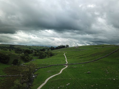 Green Grass Field Under Cloudy Sky