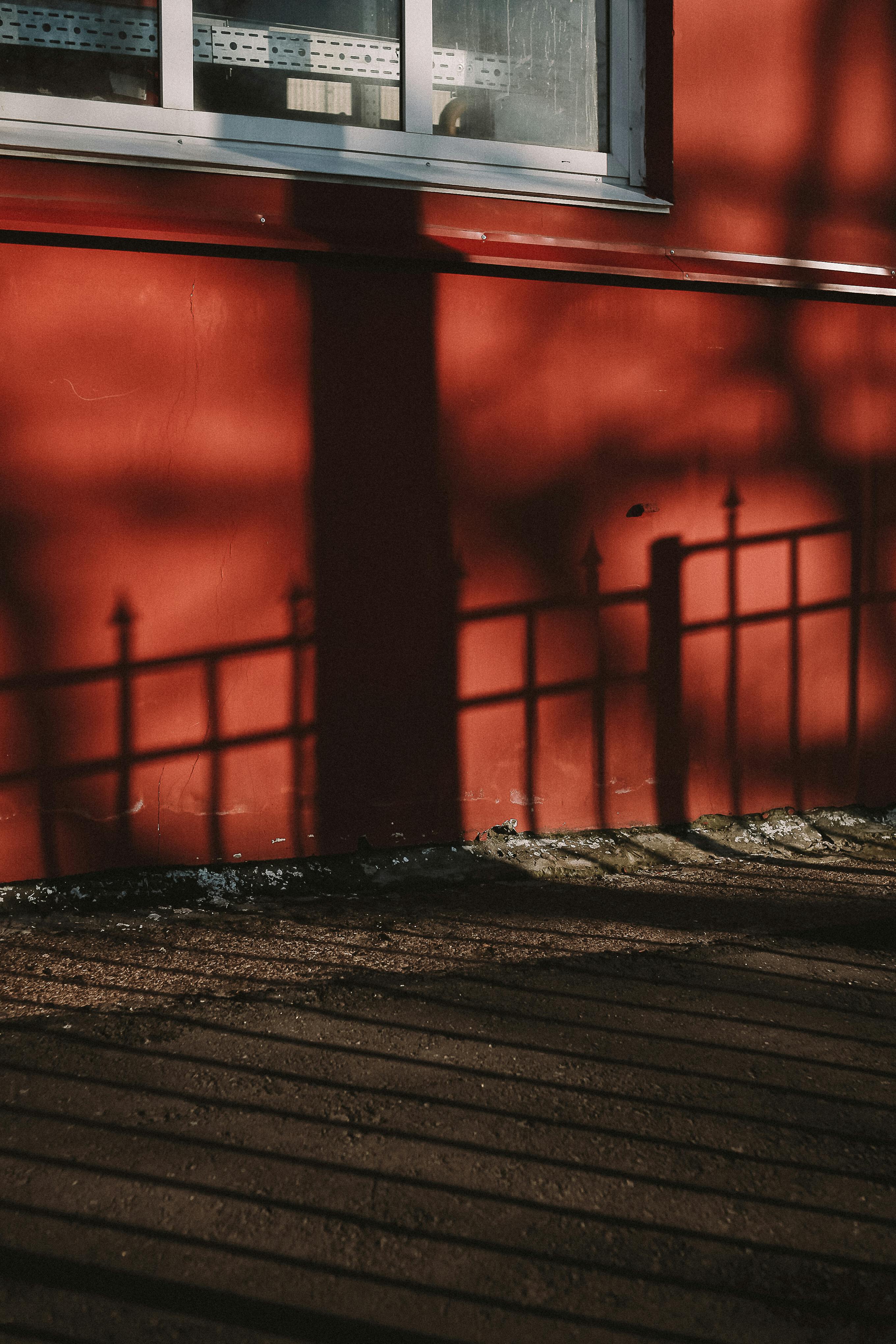 A striking image of shadows cast on a red exterior wall, creating an abstract geometric pattern.