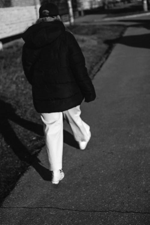 Person in Black Jacket and White Pants Walking 