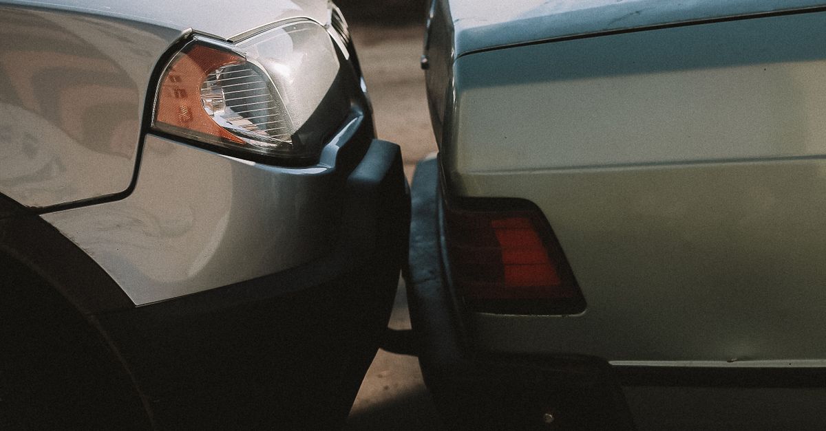 A close-up view showing the aftermath of a rear-end car collision in an outdoor setting.