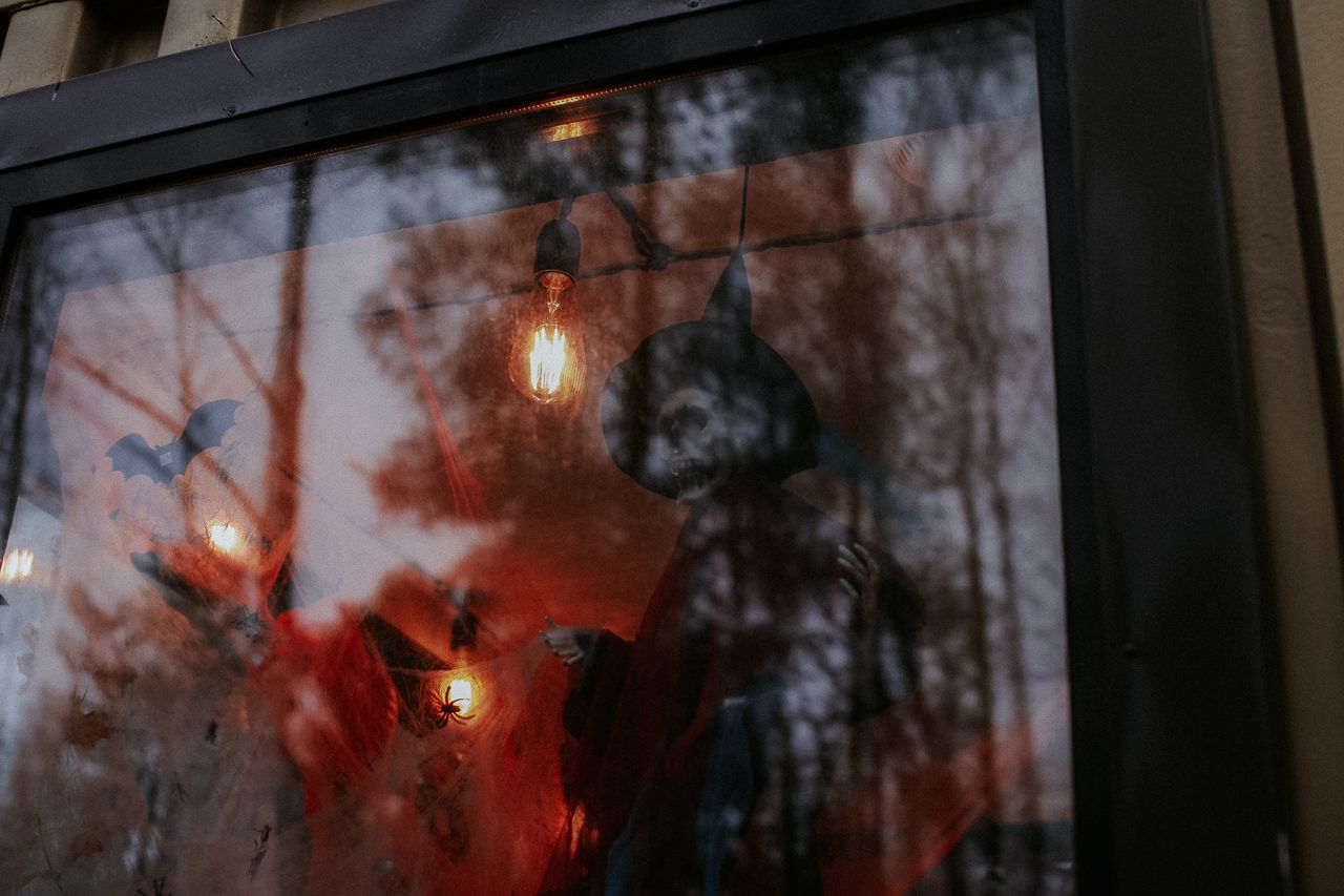 eerie halloween decor featuring a witch and bats in a glass window wit