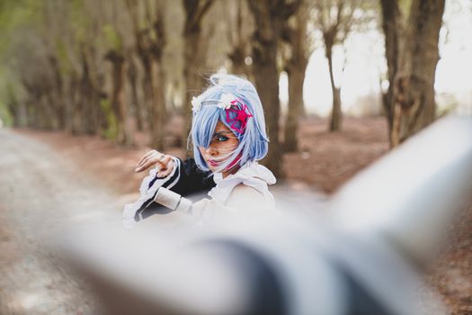 Woman in vibrant cosplay costume striking a pose in a wooded path, showcasing creativity.