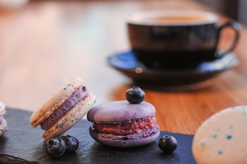 Free Close-up of colorful macarons with blueberries and coffee on a wooden table. Stock Photo