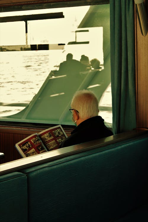 A Man Reading a Magazine Whole in a Boat Ride