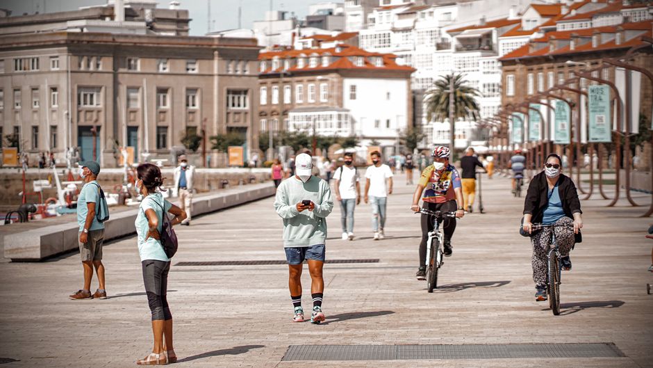 Personas caminando y paseando en bicicleta en un día soleado en el paseo marítimo de La Coruña, España.