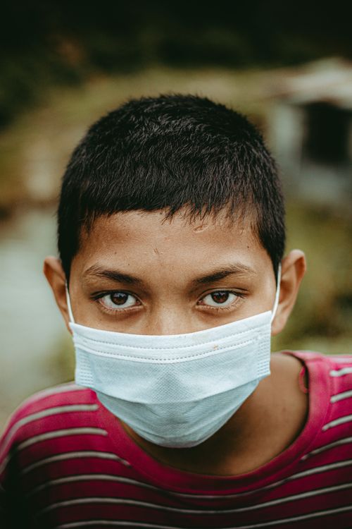 Free A close-up portrait of a young boy in a mask, expressing awareness. Stock Photo