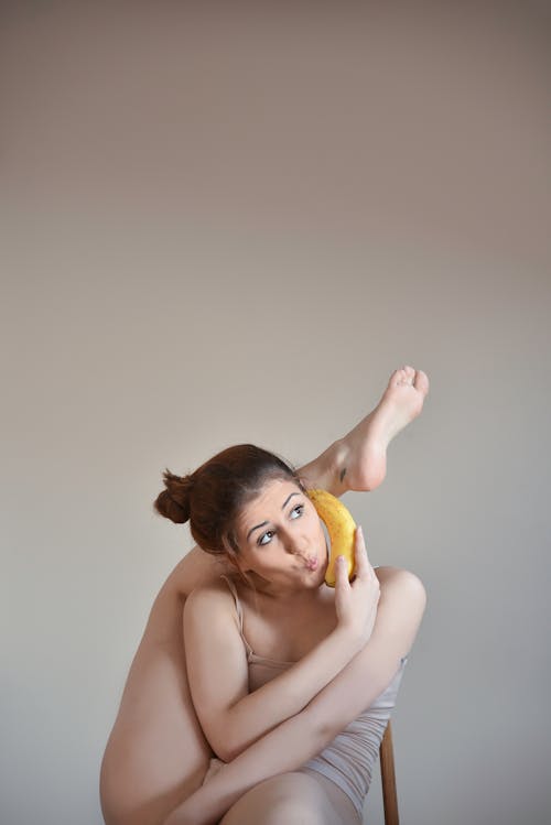 A Woman Holding a Banana while Sitting on a Chair