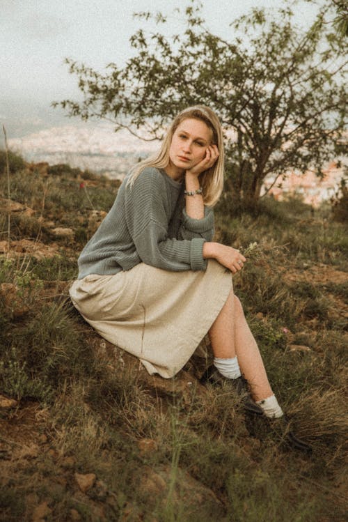 Woman Wearing Sweater and Skirt Sitting on the Grass