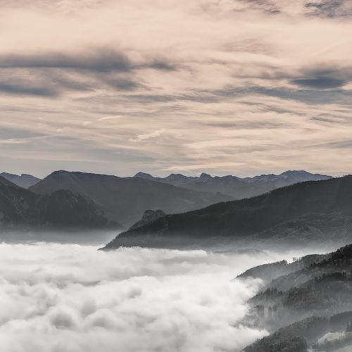 Free A breathtaking view of a mountain range enveloped in dense fog under a dramatic sky. Stock Photo